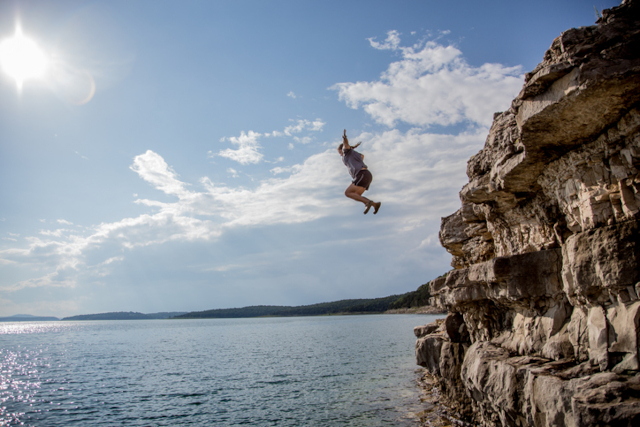 A person jumping from a high rocky cliff into the sea