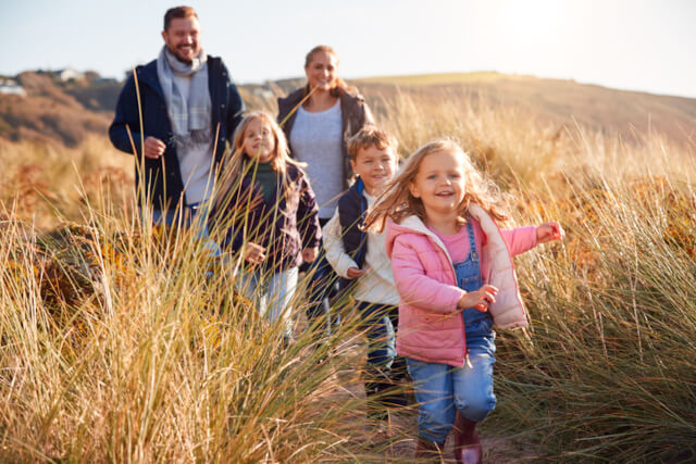 A family of four following a path through the grass on sand dunes