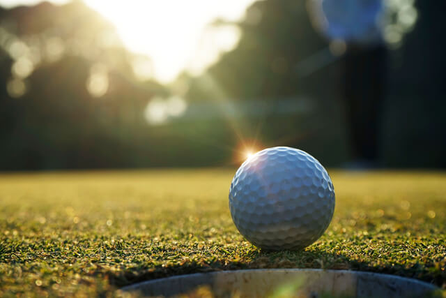 A golf ball placed next to a hole on a golf course