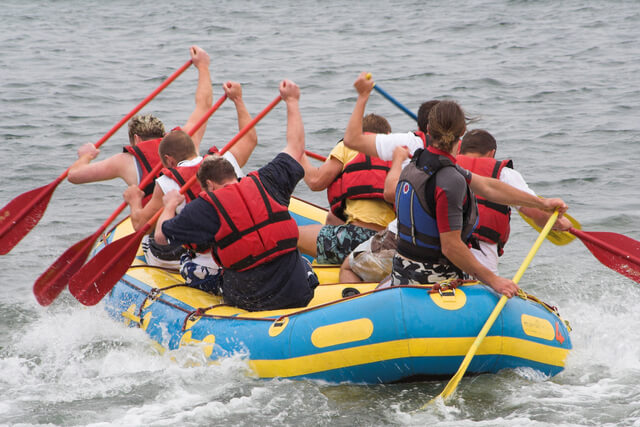 A group of people paddling in water during a raft race