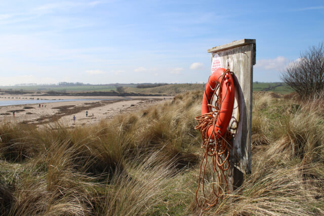 A life bouy attached to a wooden post on the sand dunes at Alnmouth Beach