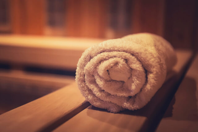 A rolled up towel placed on the bench in a wooden steam sauna