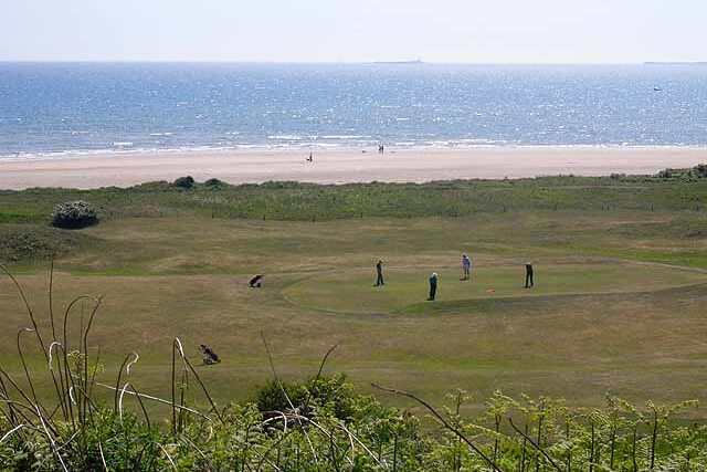 A view across the green of Alnmouth Village Golf Course with the beach and sea beyond