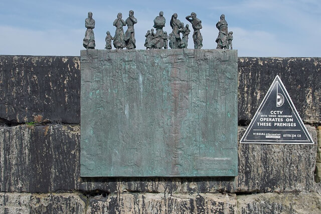 Bronze memorial statue of women and children looking out over the bay on the harbour wall in Burnmouth