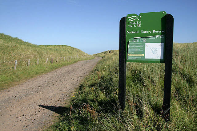 Signposted enterance to Lindisfarne National Nature Reserve alongside a gravel track
