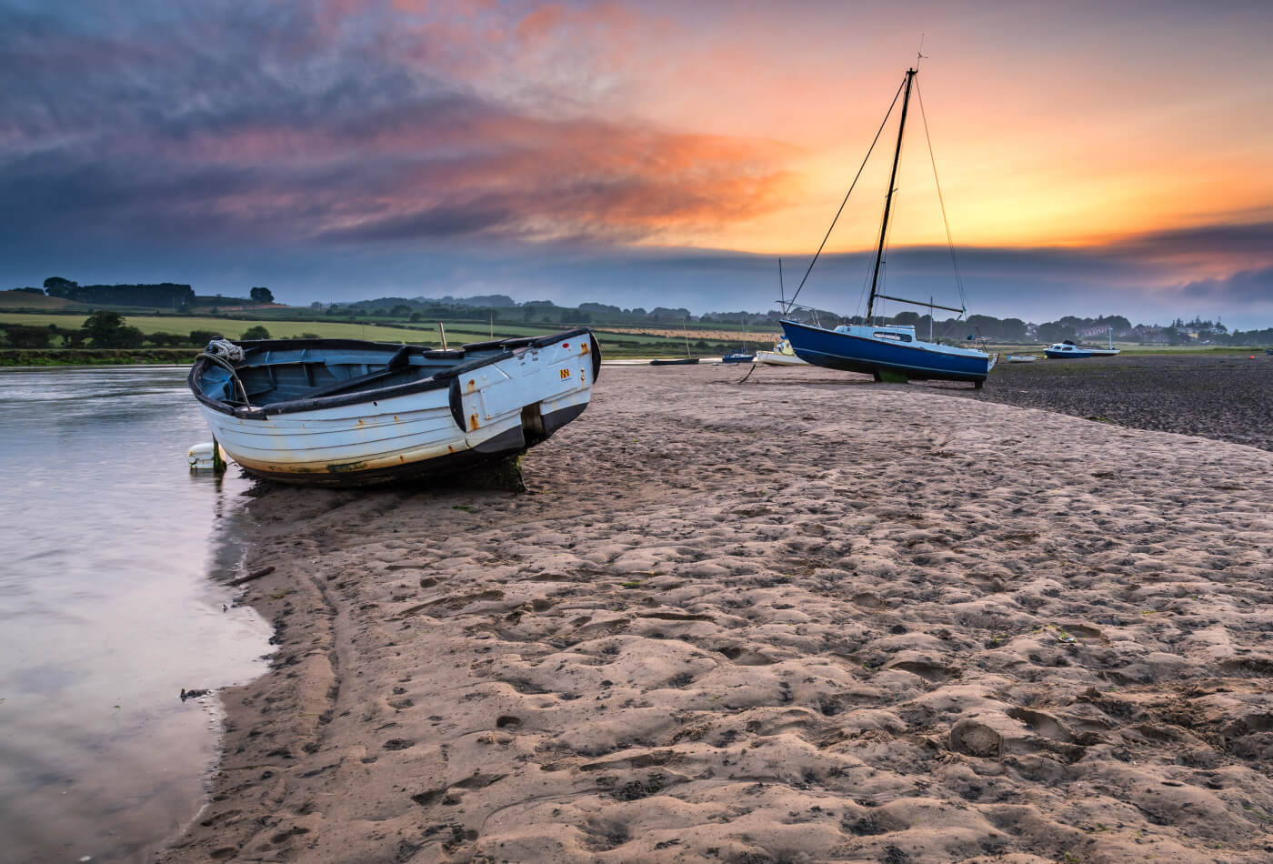 Two boats resting on the sand at sunset on Alnmouth beach