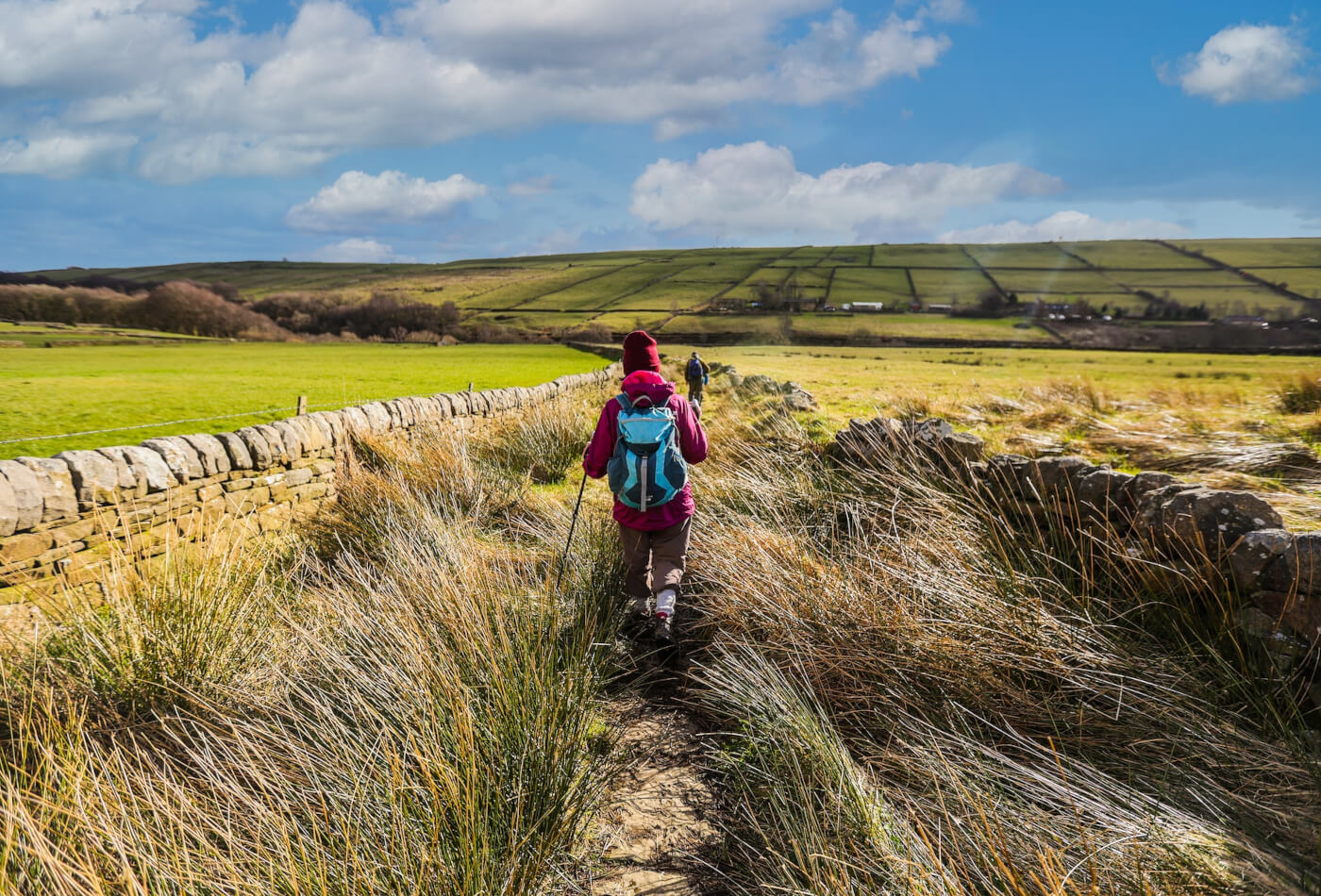 Two people in walking gear following a trail through the Northumberland National Park