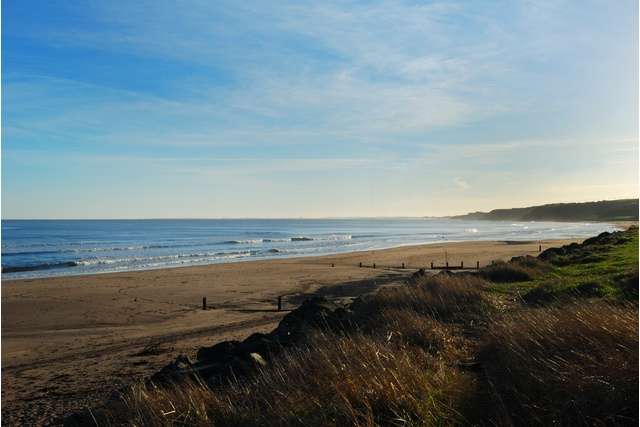 Wide stretch of Spittal Beach with marshlands, sand, and sea in shot.